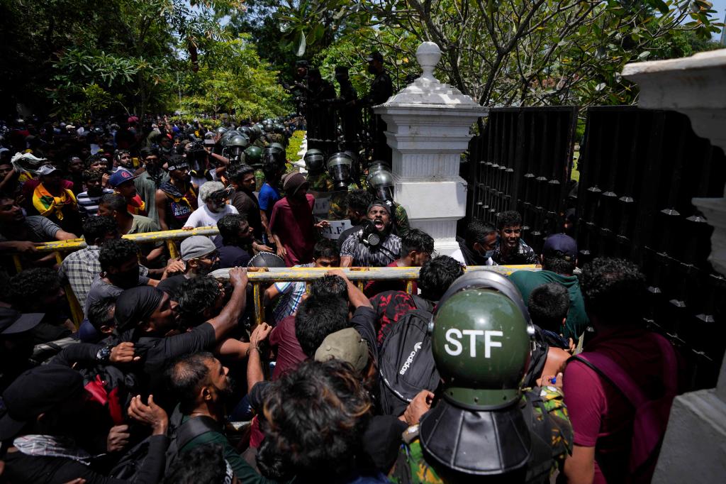 Protesters use an iron barricade to break the gate as they storm the compound of Sri Lankan Prime Minister Ranil Wickremesinghe's office.