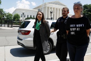 Rep. Alexandria Ocasio-Cortez being escorted by a Capitol Police officer after a protest for abortion rights outside of the Supreme Court building on July 19, 2022.