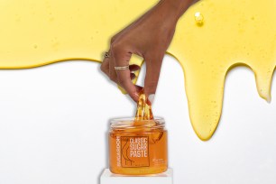 A hand pulling wax from a jar on a wax background