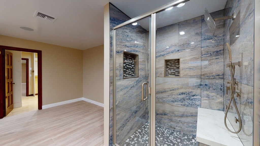 The primary bathroom with a bench installed in the rain shower.