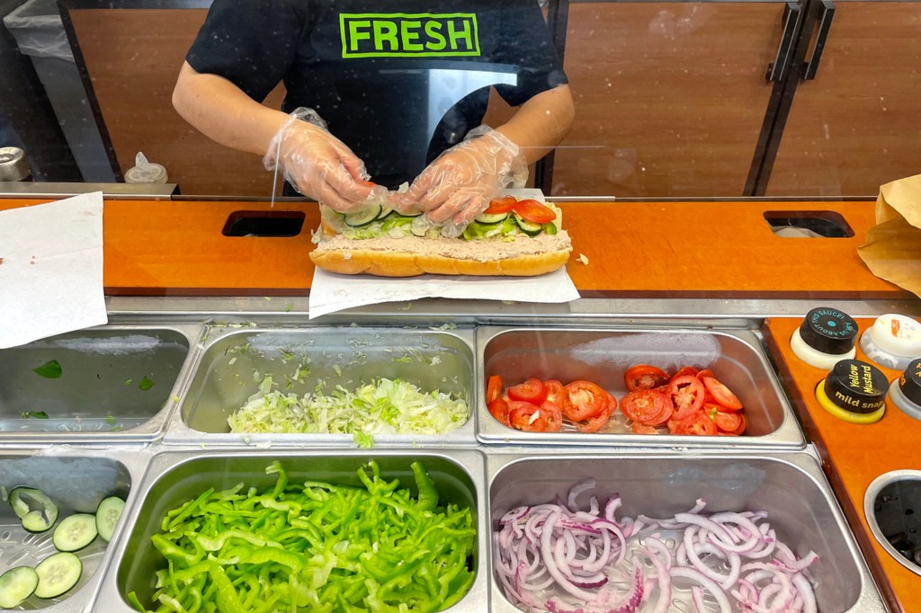 A worker prepares a tuna sandwich.