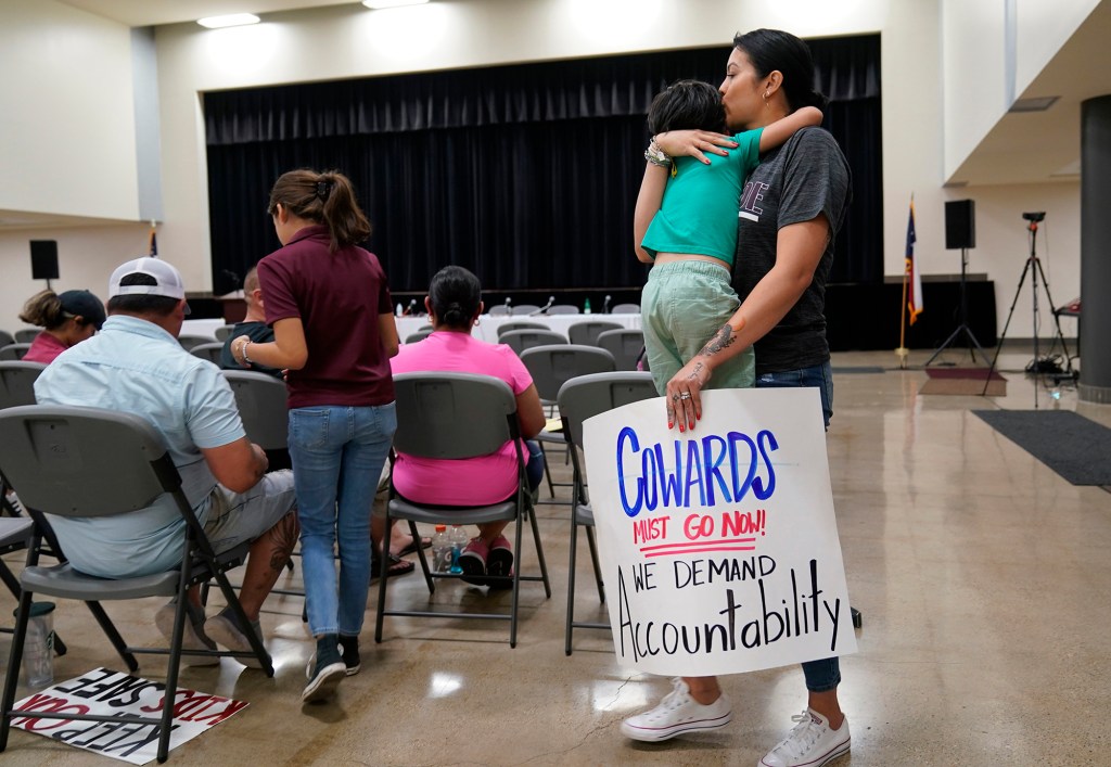 A Uvalde parent carries a protest sign as she attends a city council meeting.