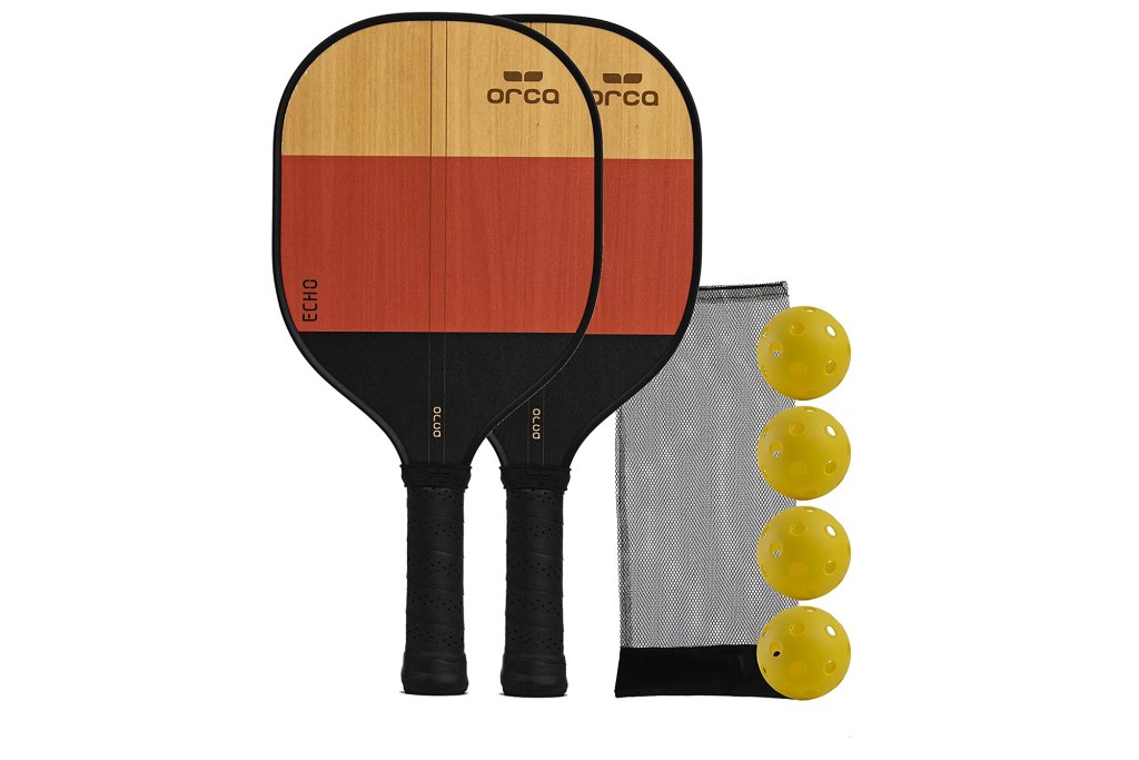 A set of two brown wood pickleball paddles and four yellow balls 