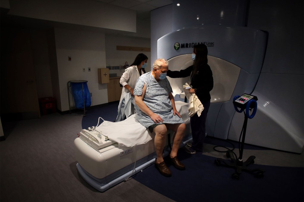 Radiation therapists Jessica Penney, left, and Jennifer Campbell, right, prepare cancer patient 