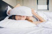 Woman trying to hide under the pillow.