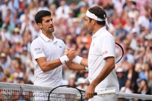 Novak Djokovic of Serbia shakes hands with Roger Federer of Switzerland at the net following victory in his Men's Singles final during Day thirteen of The Championships - Wimbledon 2019.