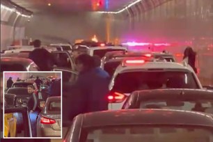 People step out of their cars parked inside the Holland Tunnel to observe a car on fire in the tunnel.