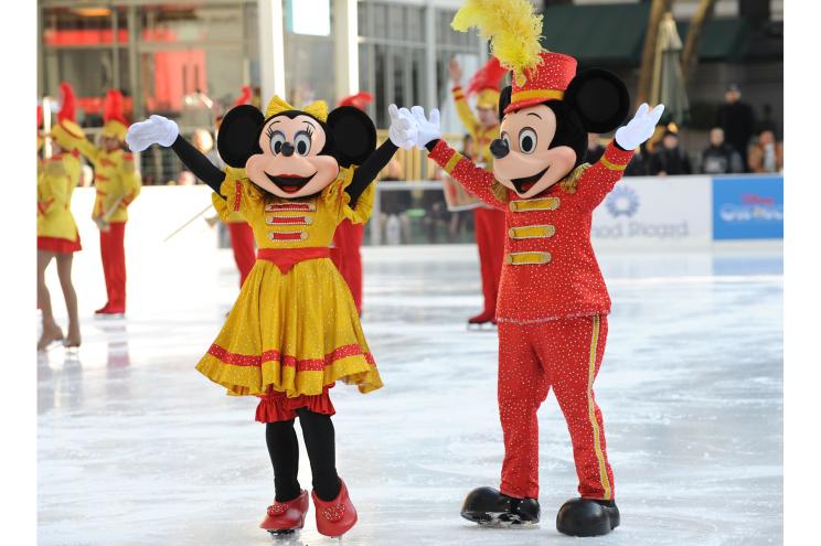 Mickey and Minnie Mouse skate together on the ice.