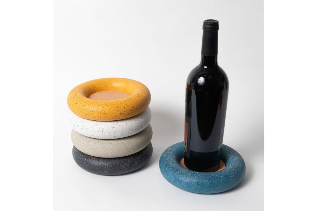 Four coasters in different colors on the left and a bottle of wine on a coaster on the right.