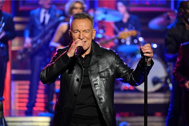 Bruce Springsteen sings onstage with the mic stand in hand.