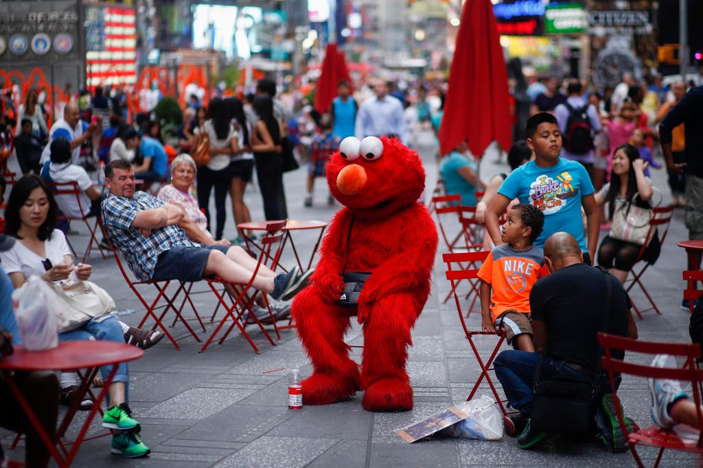 Jorge, an immigrant from Mexico, dressed as the Sesame Street character Elmo rests in Times Square, New York July 29, 2014.