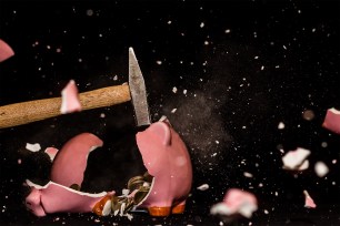 A hammer shatters a piggy bank.