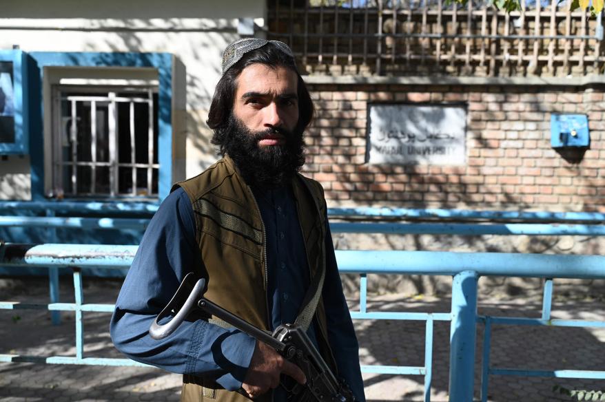 Taliban fighters stand guard as female students arrive for entrance exams.