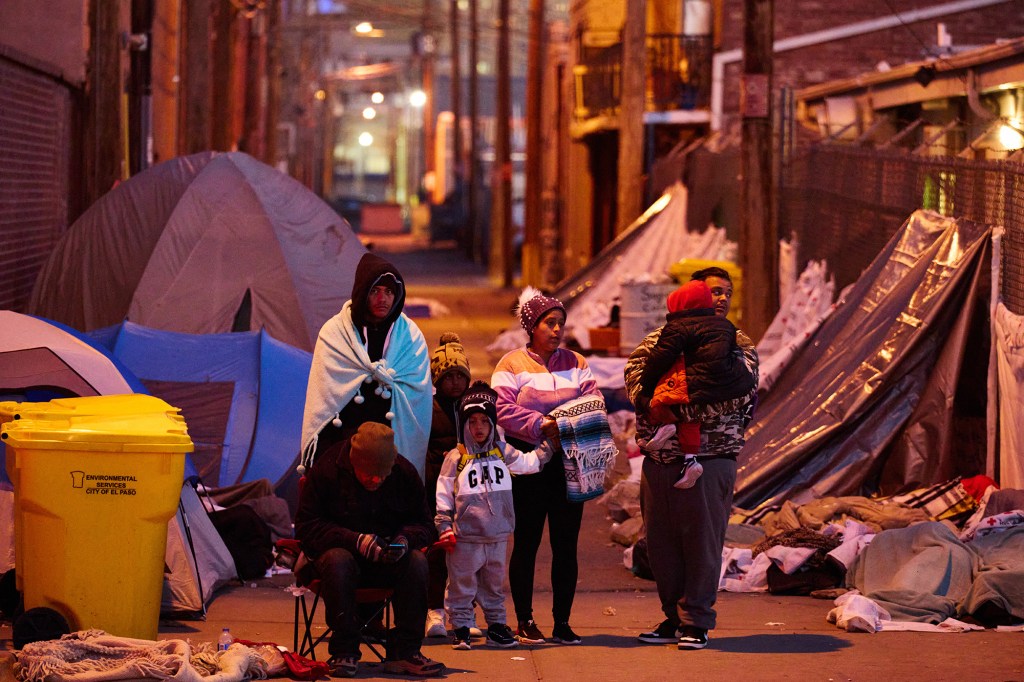 Migrants gather in an alleyway between the grounds of an overnight shelter at Sacred Heart Church church.