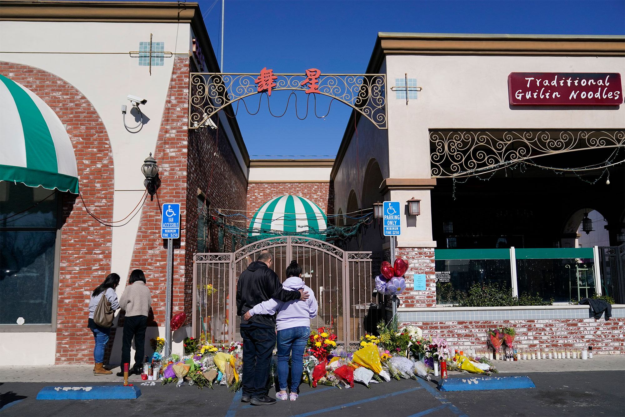 Two people stand in front of flowers placed in front of Star Ballroom Dance Studio.