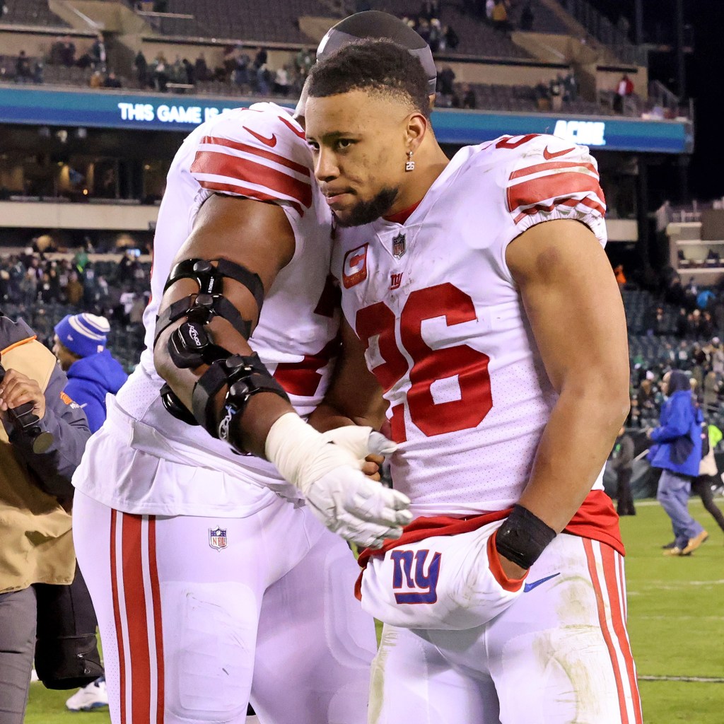 Saquon Barkley (26) is hugged by tackle Andrew Thomas after the Giants' loss to the Eagles on Jan. 21, 2023.