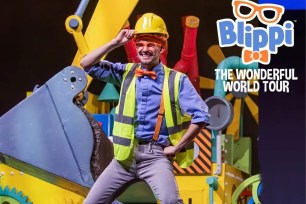 Blippi poses for a photo while wearing a hard hat.