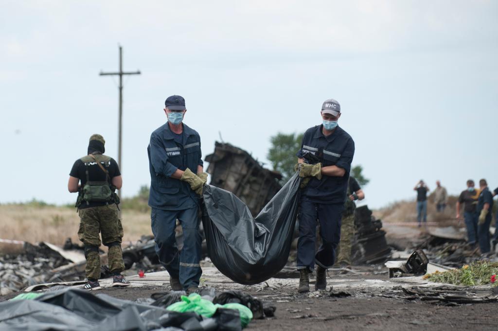 Ukrainian emergency workers carry a victim's body in a bag, at the crash site of Malaysia Airlines Flight 17 near the village of Hrabove, Russian-controlled Donetsk region of eastern Ukraine, Sunday, July 20, 2014.