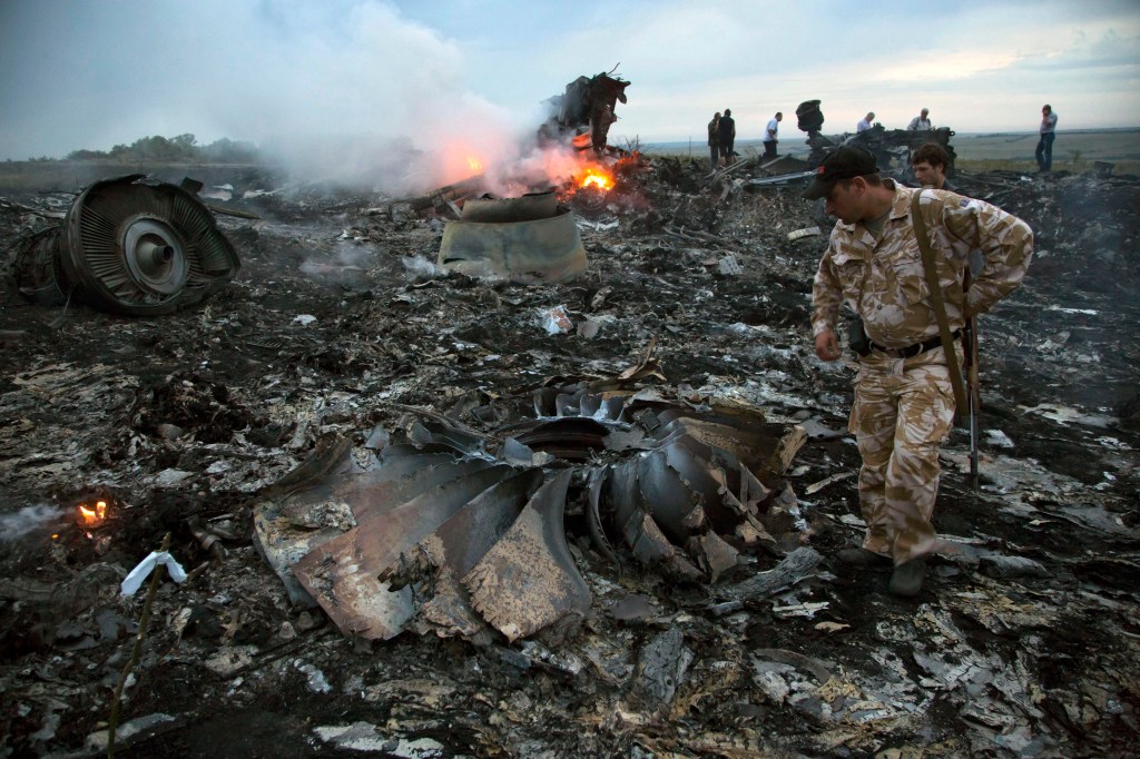 People walk amongst the debris at the crash site of a passenger plane near the village of Grabovo, Ukraine, July 17, 2014.