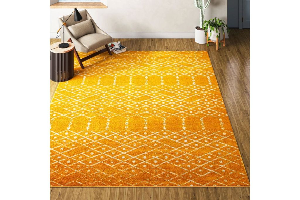 Yellow and white rug on a hardwood floor with a chair in the corner.