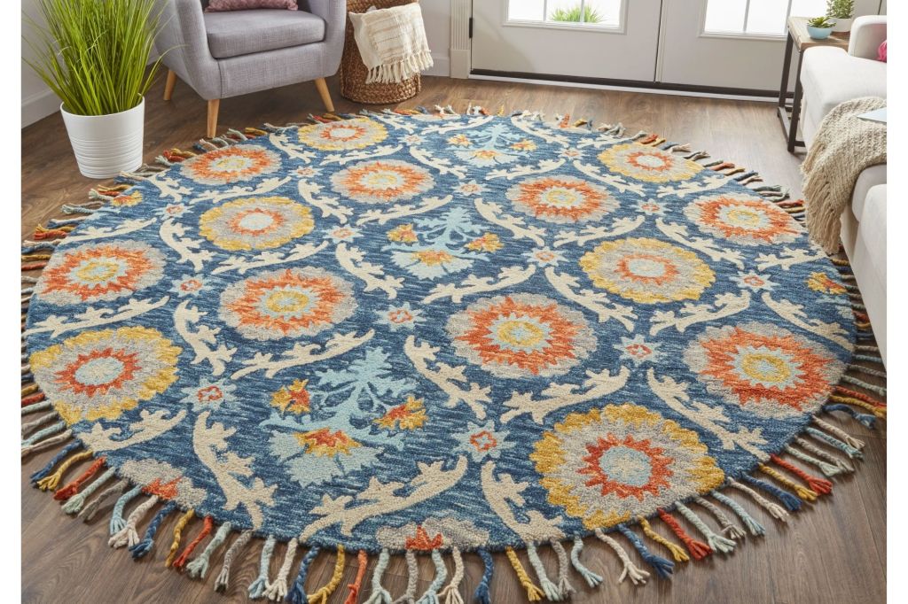 Round blue and orange rug in a room with a grey chair.