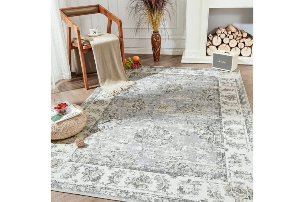 Distressed rug in a room with a chair and firewood logs.