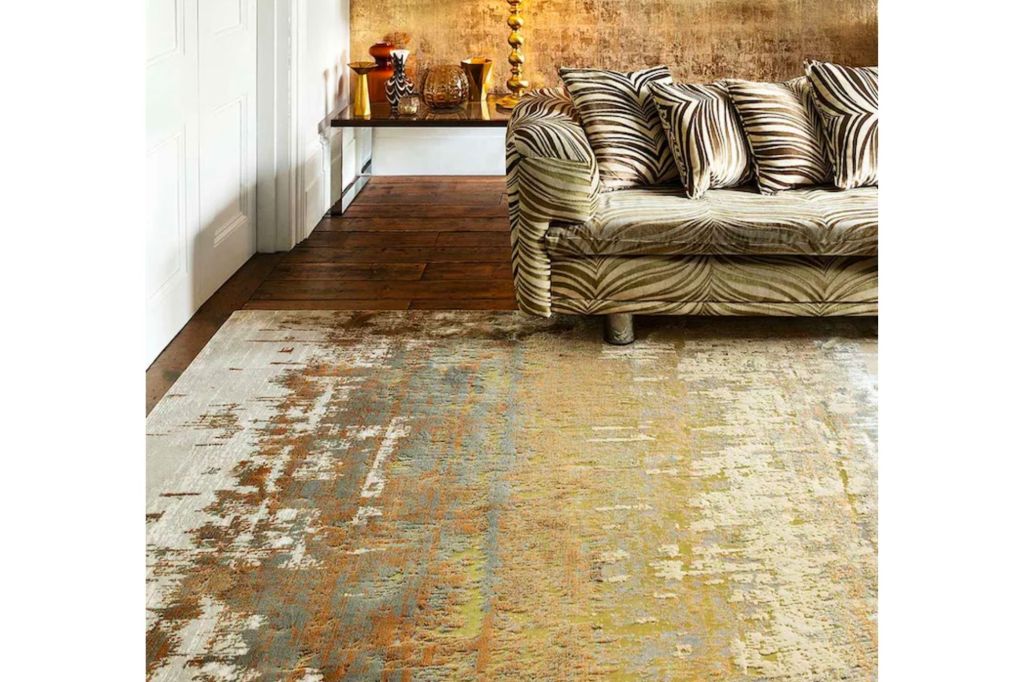 Gold vintage style rug in a room with grey velvet couch.