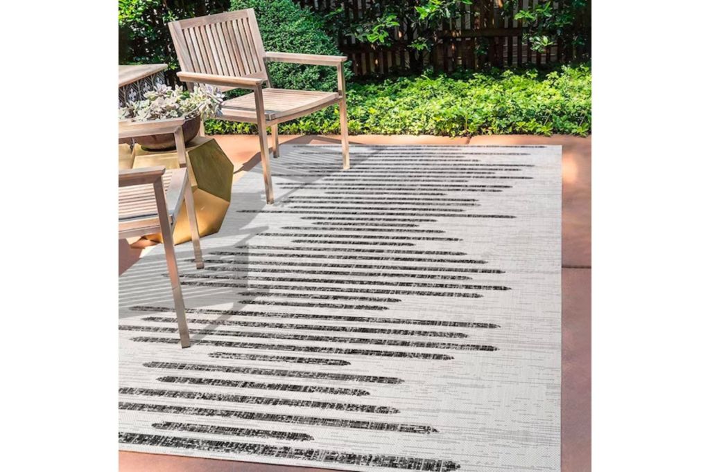 Modern style rug outside in front of two wooden chairs.