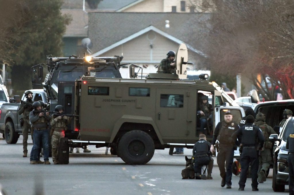 Law enforcement officers aim their weapons at a home during a standoff in Grants Pass, Ore., on Jan. 31, 2023.