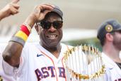 Dusty Baker tips his hat as he holds the World Series trophy.