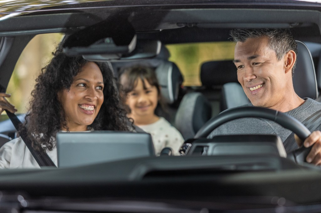 Cheerful family enjoying road trip in car.