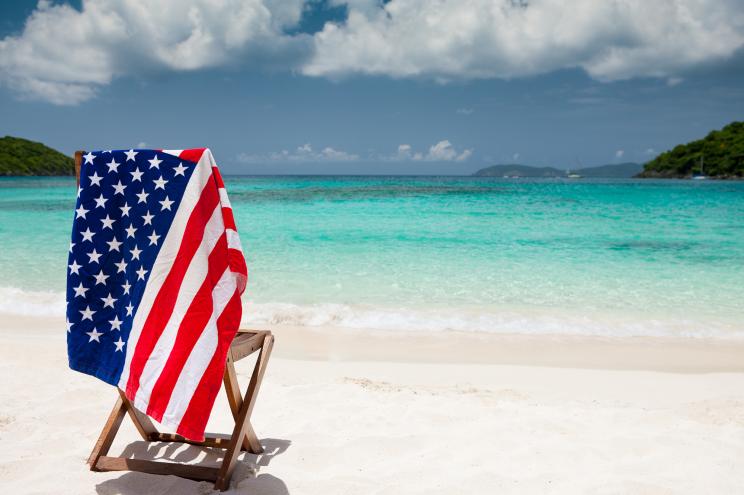 single teak chair and a towel with American flag on it at a beach in US Virgin Islands