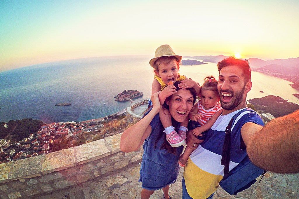 Family with two little daughters travel in nature, making selfie, smiling