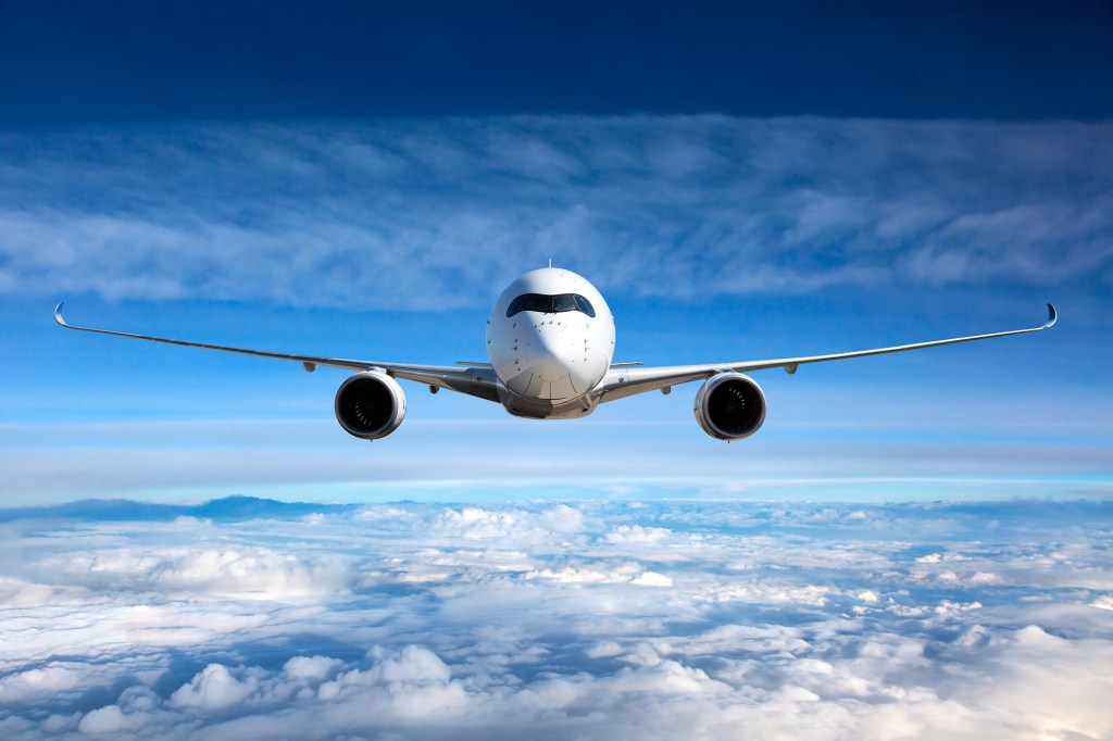 Front view of aircraft in flight. The passenger plane flies high above the clouds.