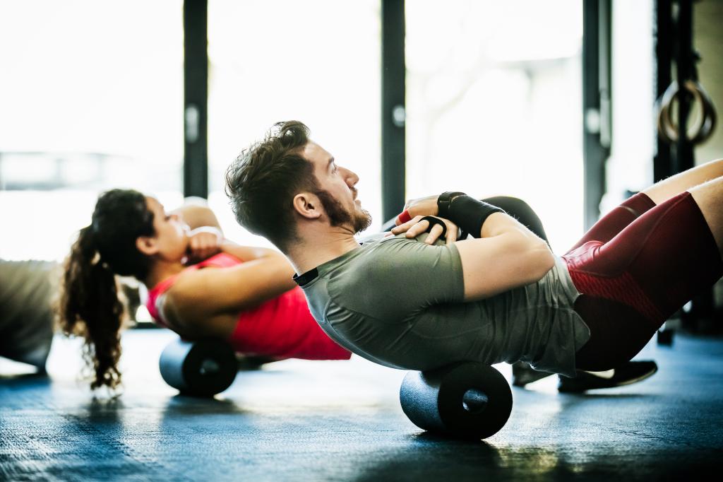 A young group of gym goers staying fit by performing floor exercises together.