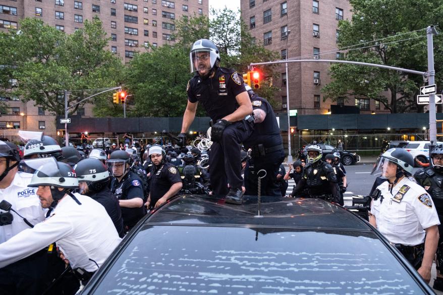 A police officer on top of a car during the protest.