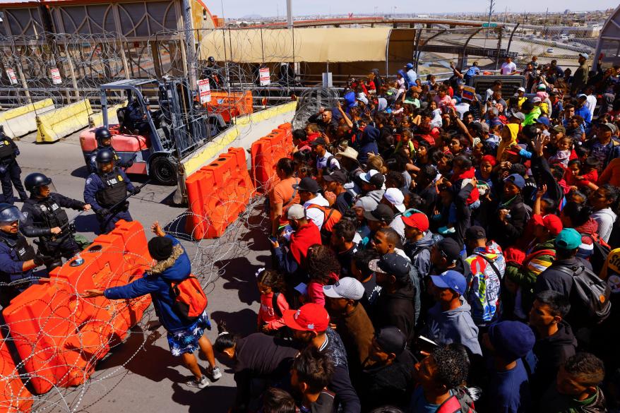 Police stand guard as migrants, mostly from Venezuela, take part in a protest at the Paso del Norte international bridge to request asylum in the United States.