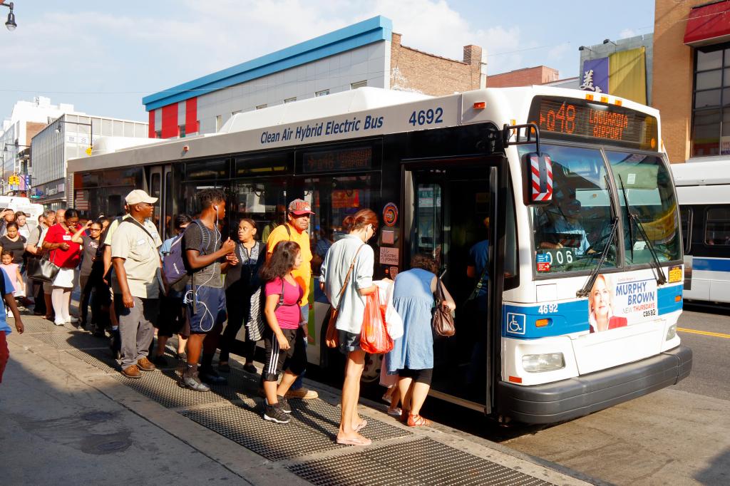 New Yorkers queue to board a NYC Transit bus in Flushing, New York.