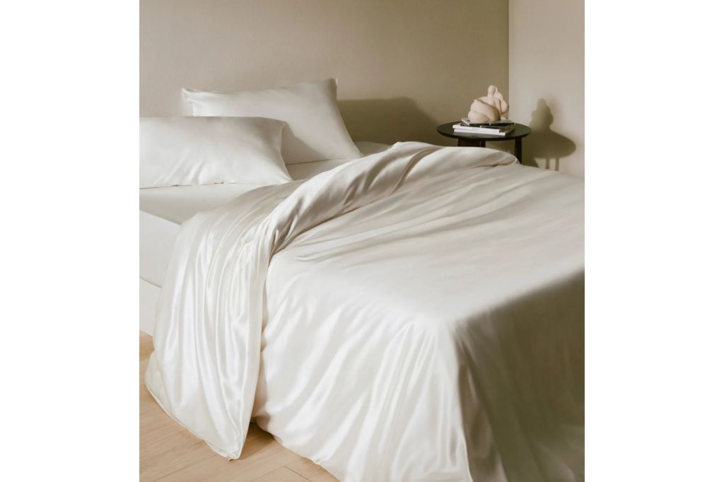 A bed covered in white silk sheets