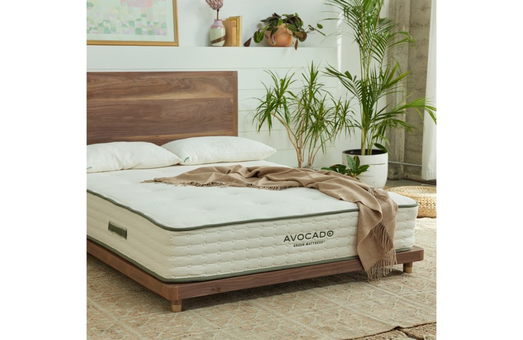 An Avocado mattress sits on a wooden bedframe