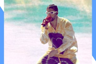 Bad Bunny performs onstage while wearing sunglasses.