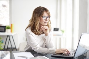 A middle-aged woman uses her laptop to research debt consolidation.