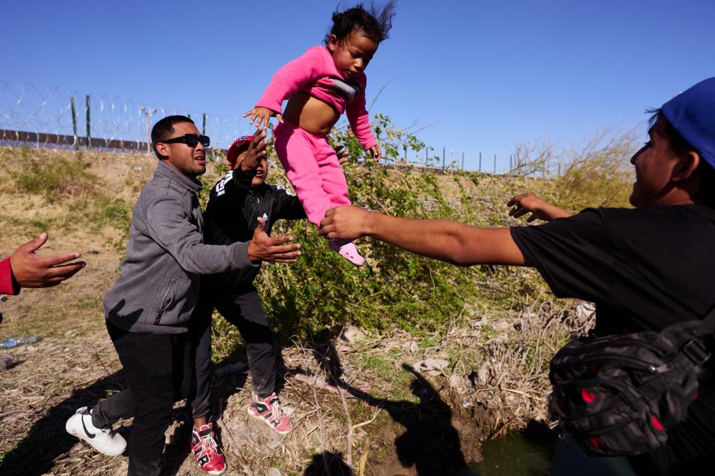 Children are tossed over the Rio Grande River after migrants marched from the National Institute of Migration to a gate at the U.S.-Mexico Border Wall in the hopes of giving themselves up for processing by U.S. Customs and Border Protection officers in Mexico.