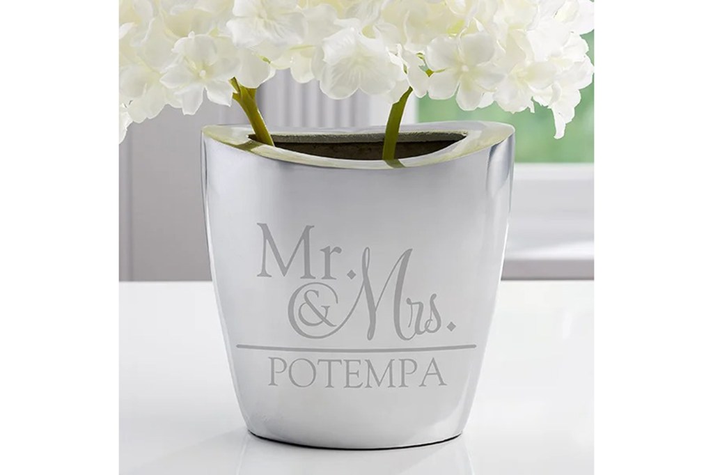 silver floral vase with engraving on front and plants inside