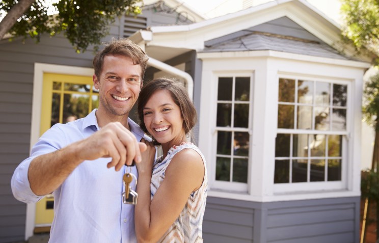 New homebuyers pose with keys after being approved for a mortgage