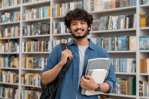 College student stands in a library.