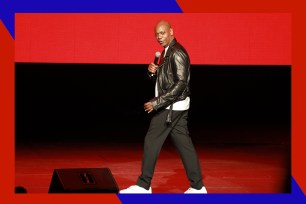 Comedian Dave Chappelle prowls the stage with a microphone in hand.