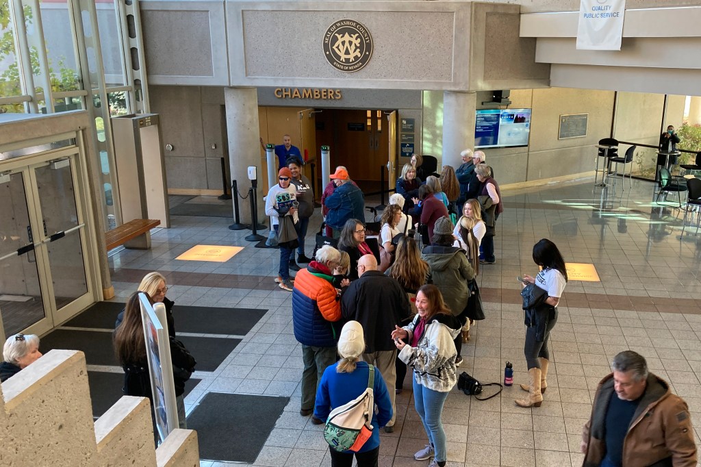 People line up outside outside the Washoe County Commission chambers to demand a hand count of ballots .