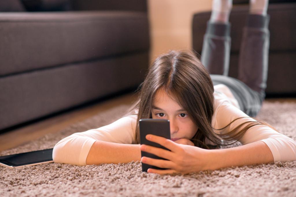 A young girl is entranced by her smartphone.