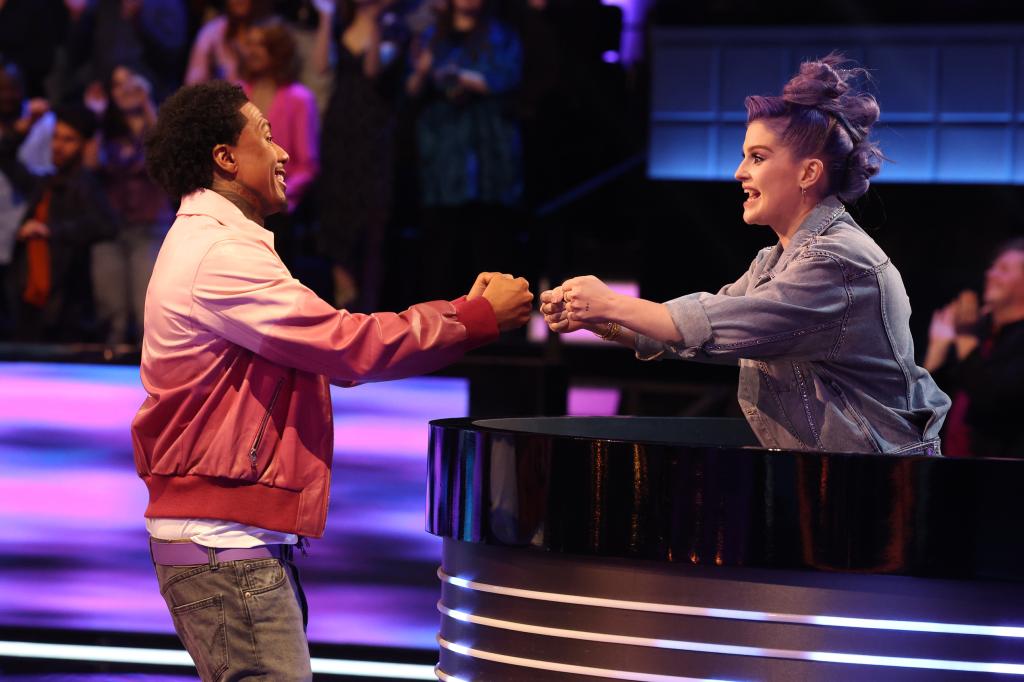 Kelly Osbourne and Nick Cannon fist pounding each other while smiling. 